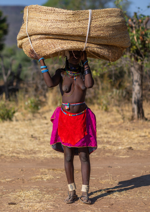 Muhakaona tribe woman carrying a heavy basket on her head, Cunene Province, Oncocua, Angola