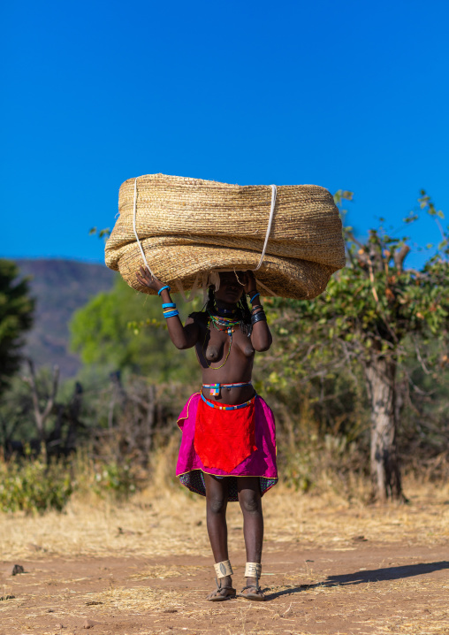 Muhakaona tribe woman carrying a heavy basket on her head, Cunene Province, Oncocua, Angola