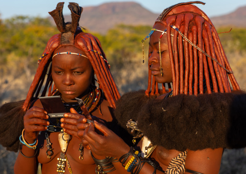 Himba tribe women looking at polaroids, Cunene Province, Oncocua, Angola