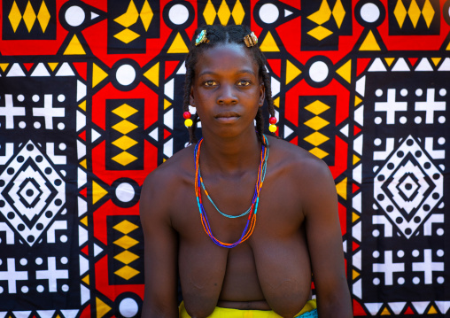 Portrait of a mudimba tribe woman in front of a colorful printed cloth, Cunene Province, Cahama, Angola