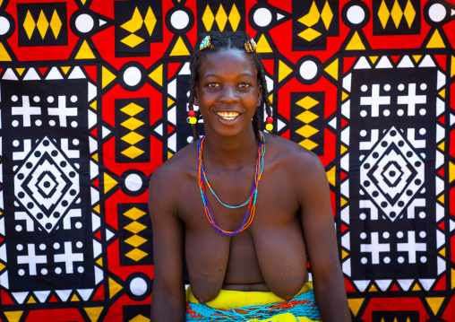 Portrait of a smiling mudimba tribe woman in front of a colorful printed cloth, Cunene Province, Cahama, Angola