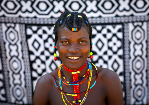 Portrait of a smiling mudimba tribe woman in front of a printed cloth, Cunene Province, Cahama, Angola
