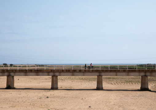 Angolan men crossing a brige over a dry river, Namibe Province, Namibe, Angola