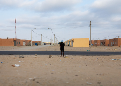 Angolan woman standing in front of popular and middle class new houses, Namibe Province, Tomboa, Angola