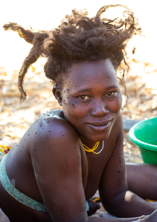 Nguendelengo tribe woman puting oil in her hair to make traditional buns, Namibe Province, Capangombe, Angola
