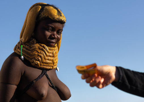 Mumuhuila tribe woman receiving money from a tourist who took pictures of her, Huila Province, Lubango, Angola