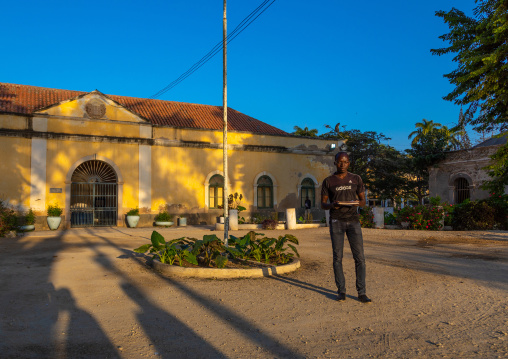 Angolan student reading a book in front of an old portuguese colonial warehouse, Benguela Province, Benguela, Angola