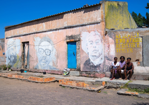 Women in front of an old propaganda wall painting with Fidel Castro Jose Eduardo dos Santos and Leonid Brejnev, Cunene Province, Cahama, Angola