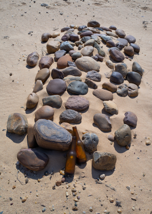 Tomb made of stones in the desert with beers offered to the dead, Cunene Province, Curoca, Angola