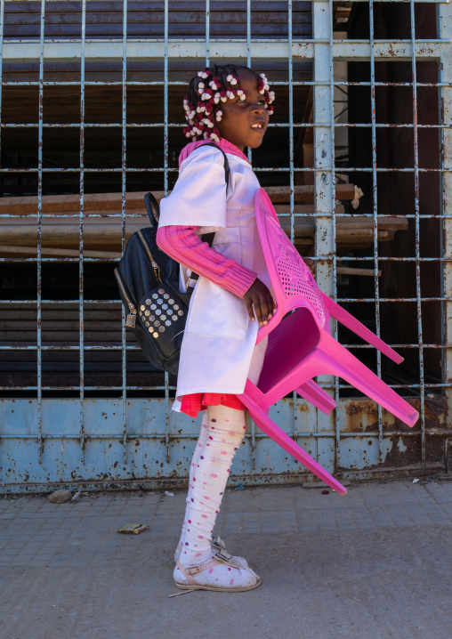 Angolan girl carrying her own chair to go to school, Huila Province, Lubango, Angola