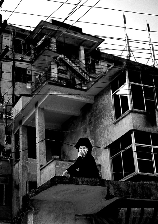Woman Sitting On A Terrace Of A Modern Building, Yuanyang, Yunnan Province, China