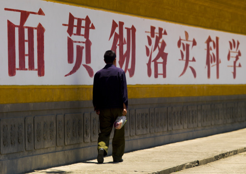 Man Walking Along A Wall With Chinese Script, Dali, Yunnan Province, China