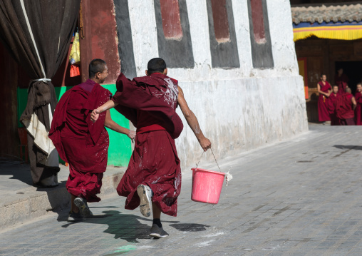Monks carrying buckets for the painting of a temple in Rongwo monastery, Tongren County, Longwu, China