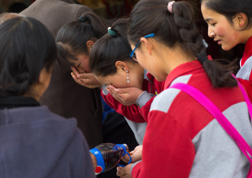 Tibetan girls drinking pepsi cola which has been blessed by the lamas in Rongwo monastery, Tongren County, Longwu, China