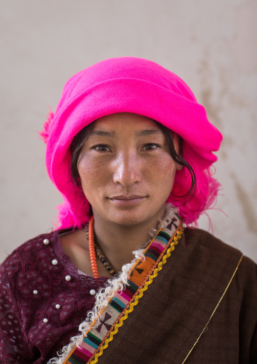 Portrait of a tibetan nomad woman with a pink headwear, Qinghai province, Tsekhog, China