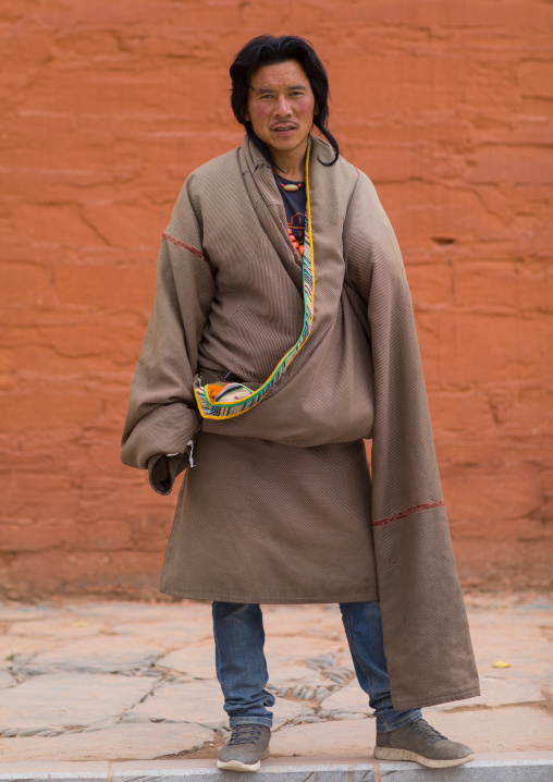 Portrait of a tibetan man wearing a coat with very long sleeves to protect from the cold, Gansu province, Labrang, China