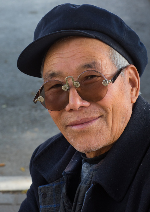 Old man with traditional sunglasses and cap, Gansu province, Linxia, China