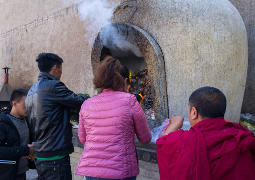 Tibetan pilgrims burning offerings in an oven in Rongwo monastery, Tongren County, Longwu, China