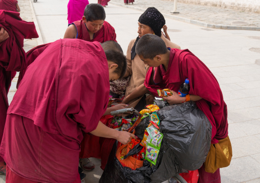 Young monks buying candies and food to a hui woman seller, Gansu province, Labrang, China