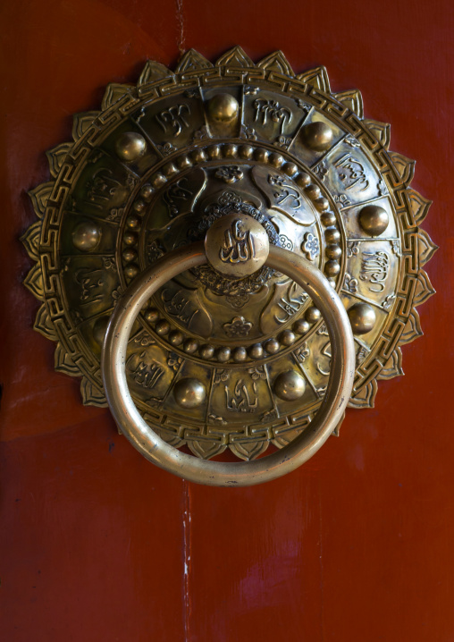 Ornate knocker with arabic scripts on traditional door in Yu Baba Gongbei islamic shrine complex, Gansu province, Linxia, China