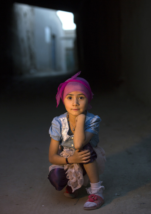 Young Uyghur Girl Squatting Alone In The Street, Yarkand, Xinjiang Uyghur Autonomous Region, China