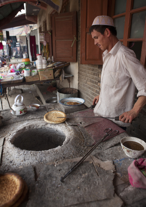 Uyghur Man Baking Traditional Bread In A Wood Stove, Keriya, Xinjiang Uyghur Autonomous Region, China