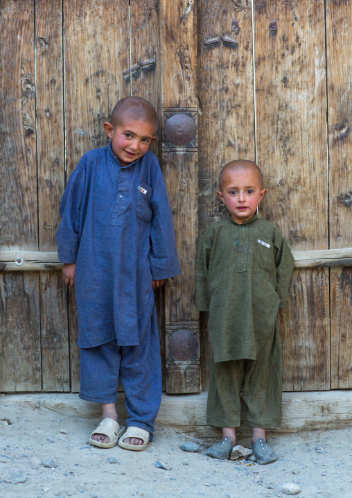Afghan boys with shaved heads standing in front of a wooden door, Badakhshan province, Khandood, Afghanistan
