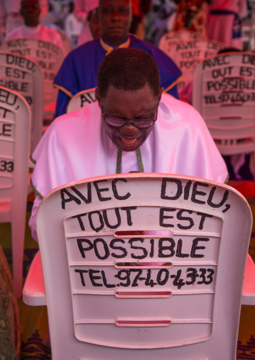 Benin, West Africa, Ganvié, celestial church of christ men praying in front of a chair with "with god everything is possible" slogan