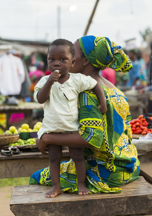 Benin, West Africa, Porto-Novo, child with his mother eating a banana in a market