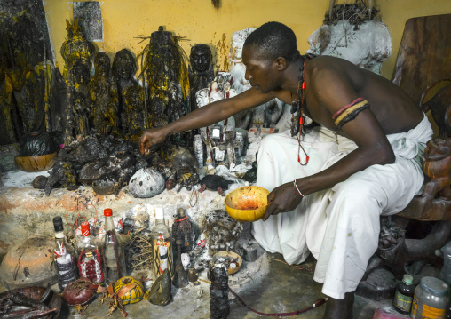 Benin, West Africa, Bonhicon, kagbanon bebe voodoo priest putting some oil on his fetish during a ceremony