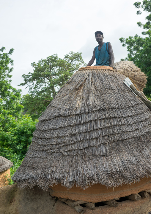 Togo, West Africa, Nadoba, man standing on the roof of a traditional tata somba house