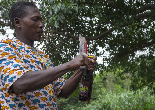 Benin, West Africa, Dankoly, a priest opens a coca cola bottle with a blooded knife during a voodoo ceremony