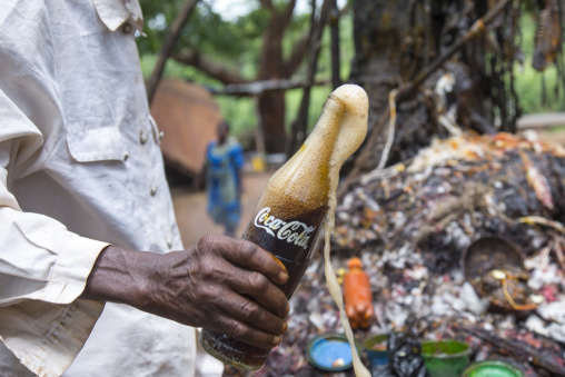 Benin, West Africa, Dankoly, a priest putting coca cola on a voodoo shrine to make an offering to the spirits