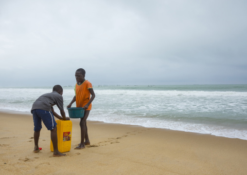 Benin, West Africa, Cotonou, children collecting sea water