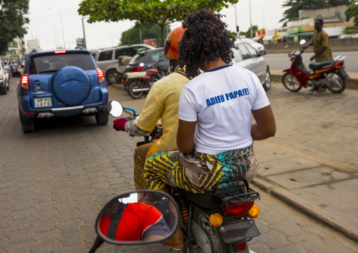 Benin, West Africa, Cotonou, woman on a motorbike with a shirt "farewell daddy" made for her dad funerals