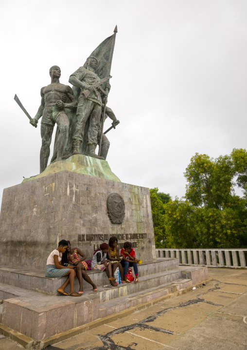 Benin, West Africa, Cotonou, group of girls sitting in front of 1977 martyrs monument made by north korean artists