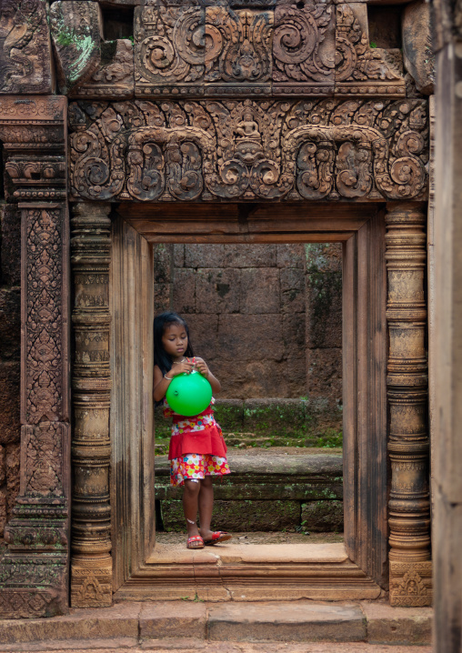 Cambodian little girl with a green balloon in Banteay Srei temple gate, Siem Reap Province, Angkor, Cambodia
