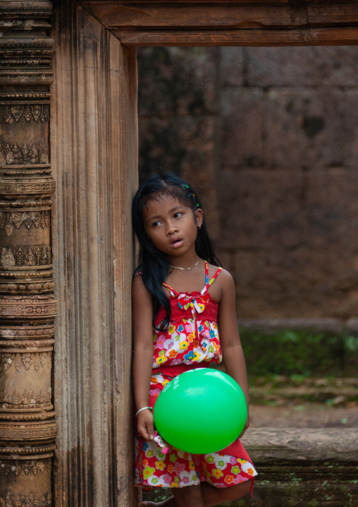 Cambodian little girl with a green balloon in Banteay Srei temple gate, Siem Reap Province, Angkor, Cambodia