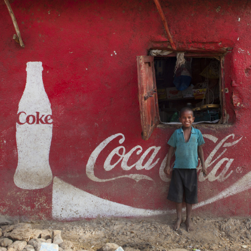 Smiling Kid Standing In Front Of A Wall Painted With A Coca Cola Advertisement, Dire Dawa, Ethiopia
