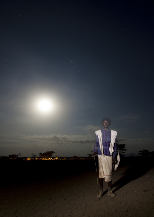 Night Shot Of A Young Karrayyu Tribe Man With Traditional Gunfura Hairstyle Under Full Moon At Gadaaa Ceremony, Metahara, Ethiopia