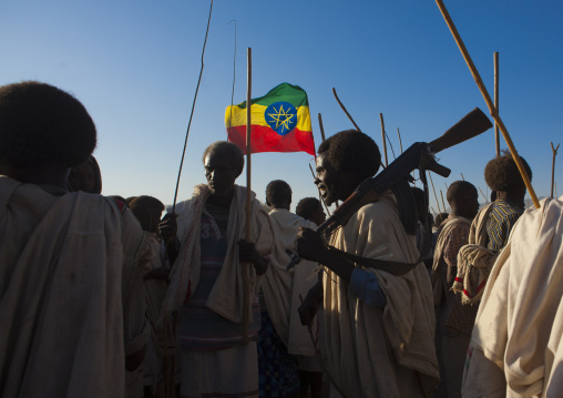 Ethiopian Flag Floating Above A Group Of Karrayyu Tribe Men, One Carrying A Kalashnikov, At Stick Fighting, During Gadaaa Ceremony, Metahara, Ethiopia