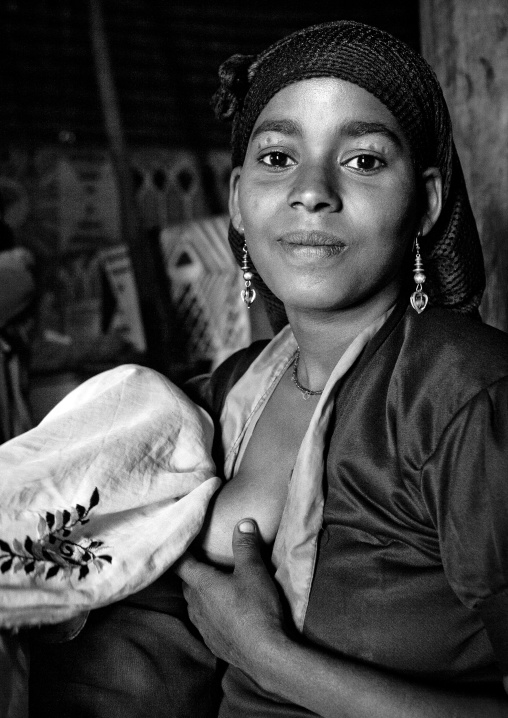 Black and white portrait of a young Ethiopian mother breastfeeding her baby, Alaba, Ethiopia