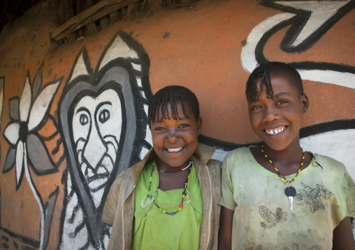 Portrait of smiling girls with toothy smiles in front of their decorated house, Alaba, Ethiopia