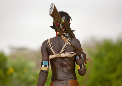 Hamer Tribe Woman Walking With  Rifle During Bull Leaping Ceremony And With Whipped Back, Omo Valley, Ethiopia