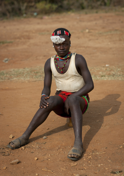 Sitting ari teenage boy with traditional ornaments omo valley Ethiopia