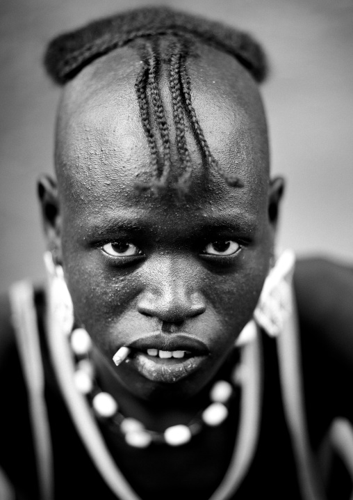 Portait of a fashionable tsemay tribe man with a traditional hairstyle posing in key afer, Omo valley, Ethiopia