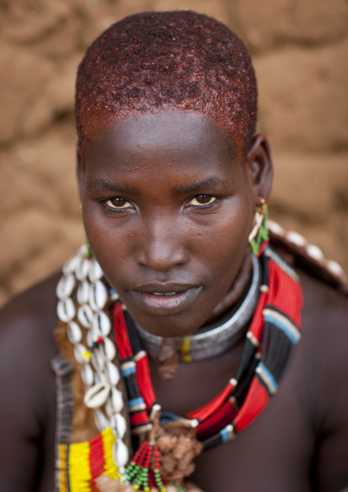 Portrait Of Traditionally Dressed Hamer Beautiful Woman Posing In Front Of Clay House  Omo Valley Ethiopia