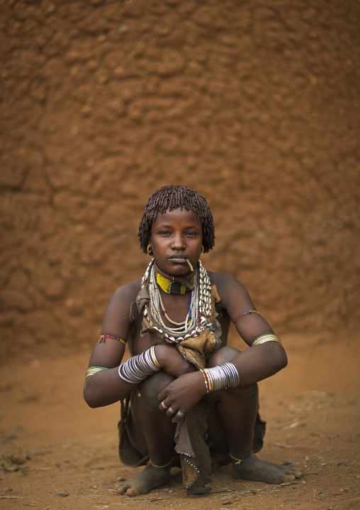 Squatting Hamer Beautiful Woman With Siwak Stick Posing In Front Of Clay House Omo Valley Ethiopia