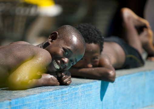 Kids with toothy smiles laying down near a swimming pool, Adama, Ethiopia