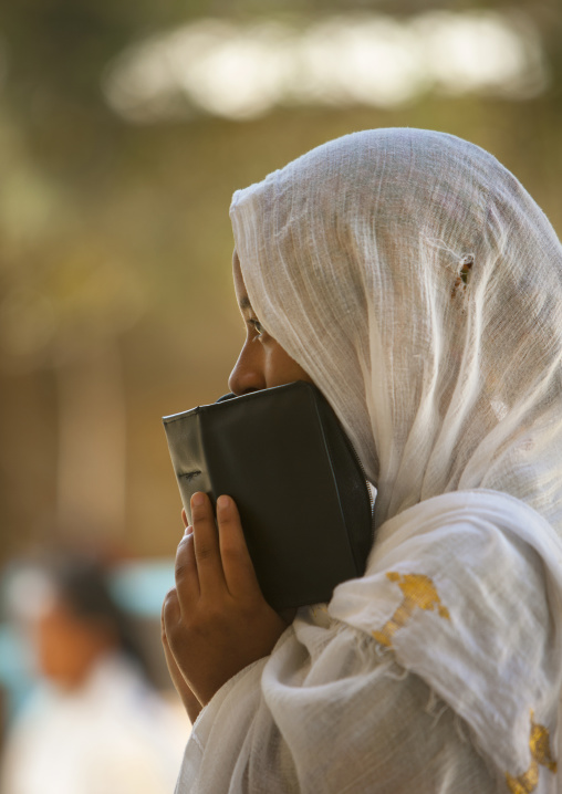 Profile portrait of an orthodox woman praying with a bible in church, Harar, Ethiopia